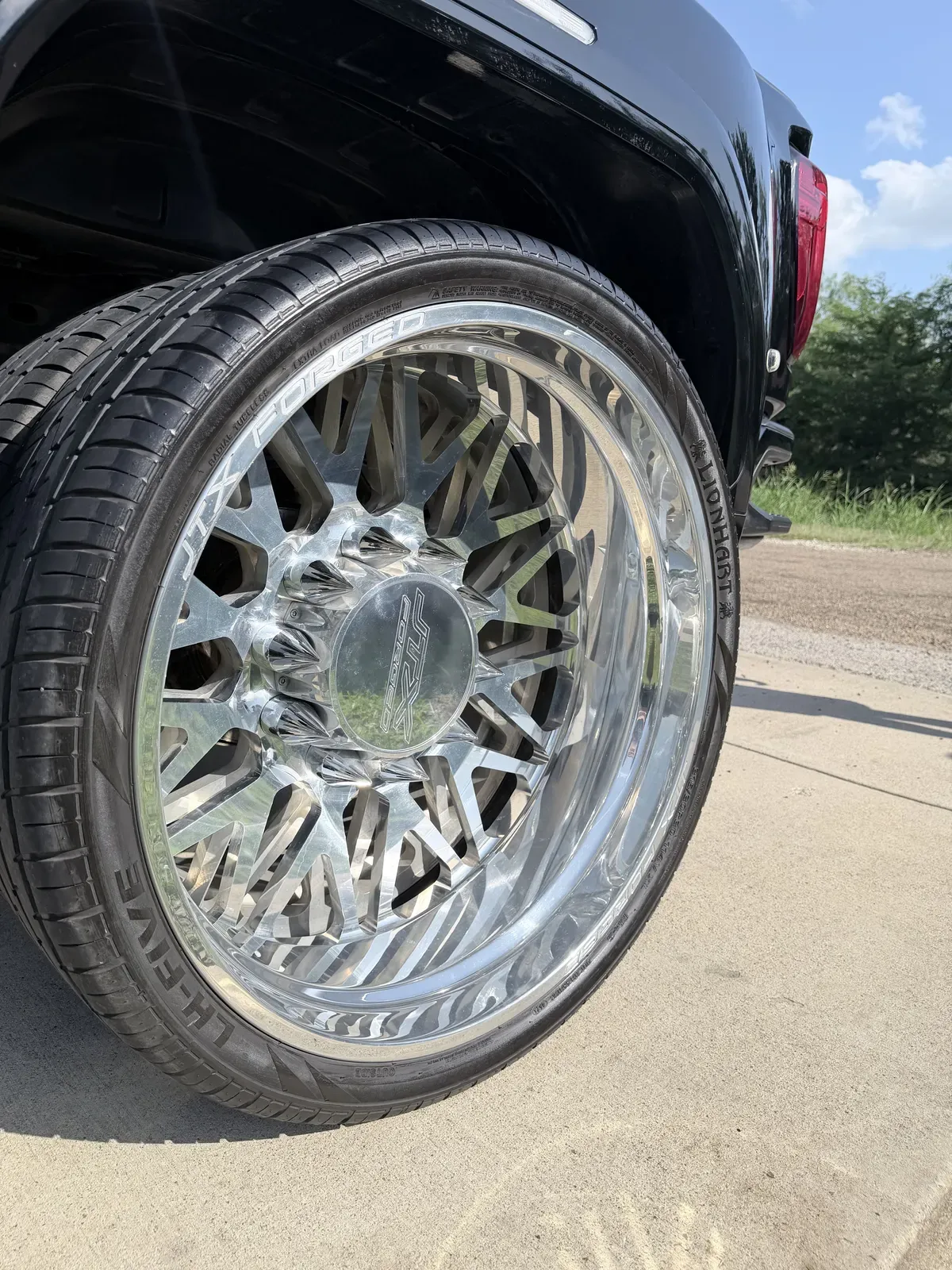 Gleaming forged aluminum wheel on a black pickup with water spots removed and tire dressed after wheel detailing