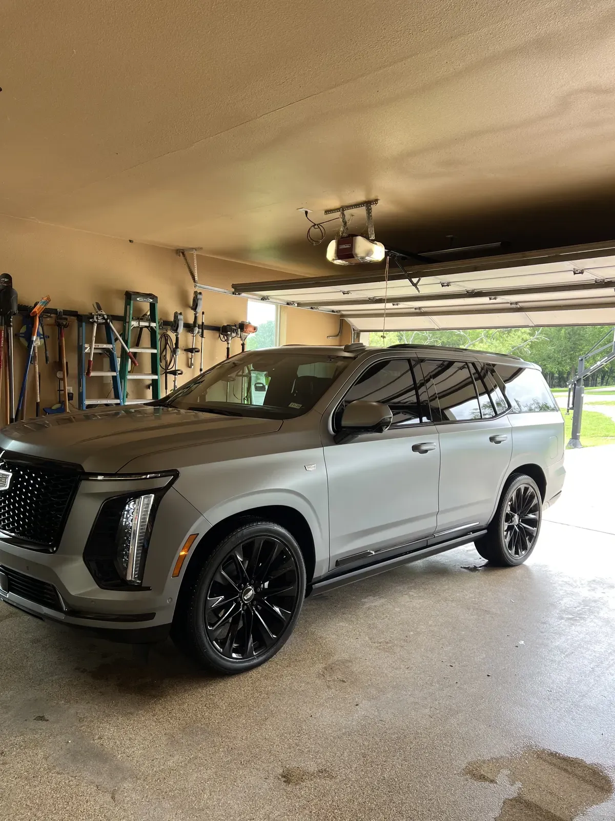 Matte gray Cadillac Escalade with gloss black wheels detailed inside a home garage
