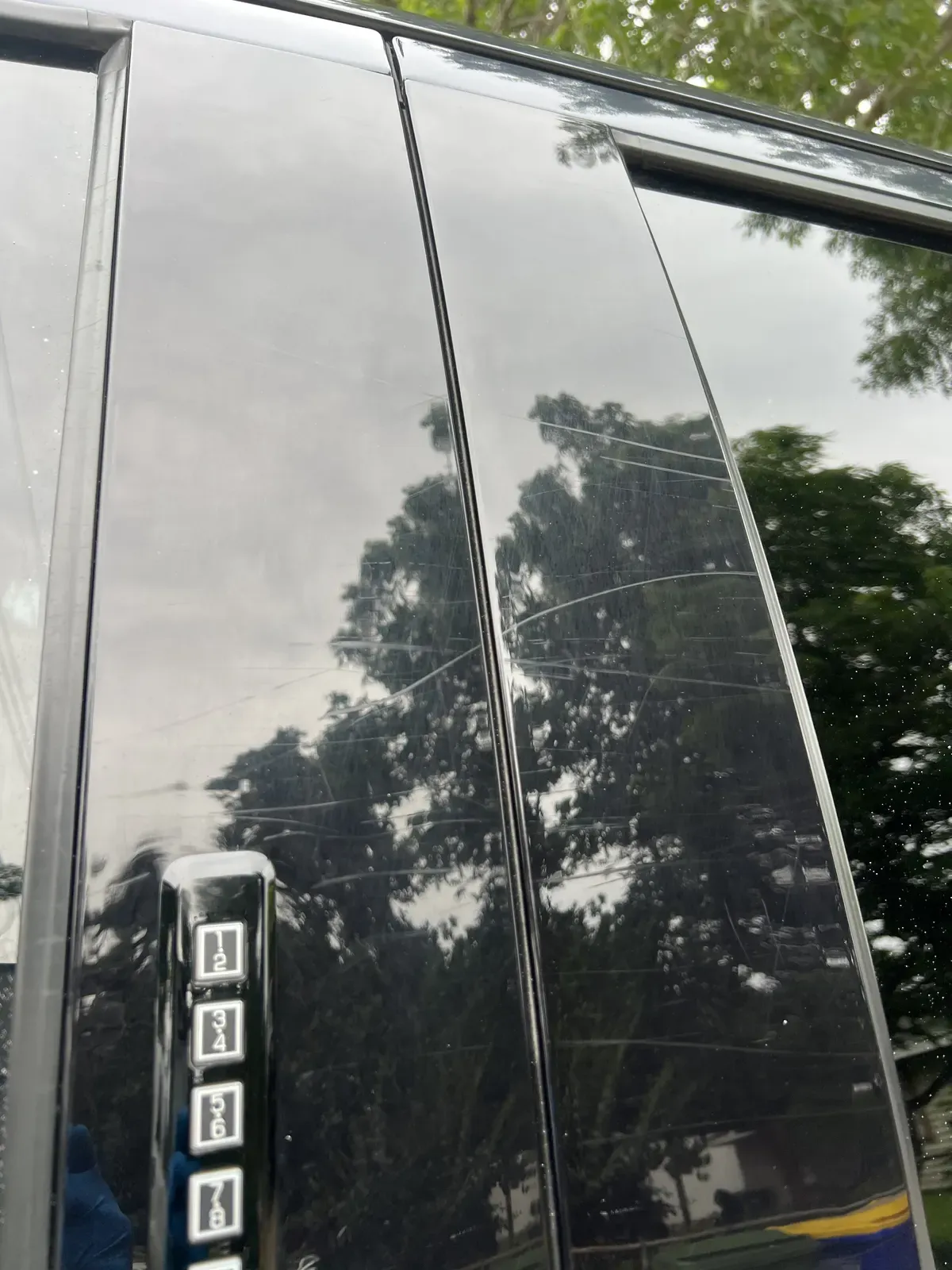 Gloss black door pillar trim covered in scratches and swirl marks before paint correction
