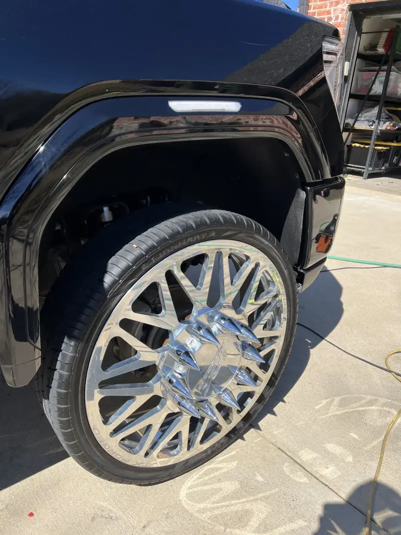 Polished aftermarket wheel and glossy black paint on lifted GMC Sierra Denali HD after ceramic coating