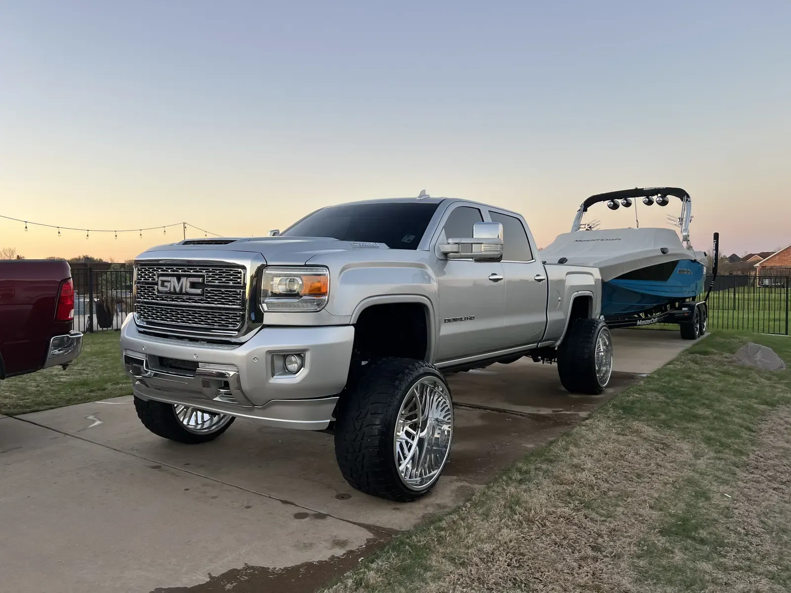 Lifted GMC Sierra Denali HD towing a covered MasterCraft boat at sunset