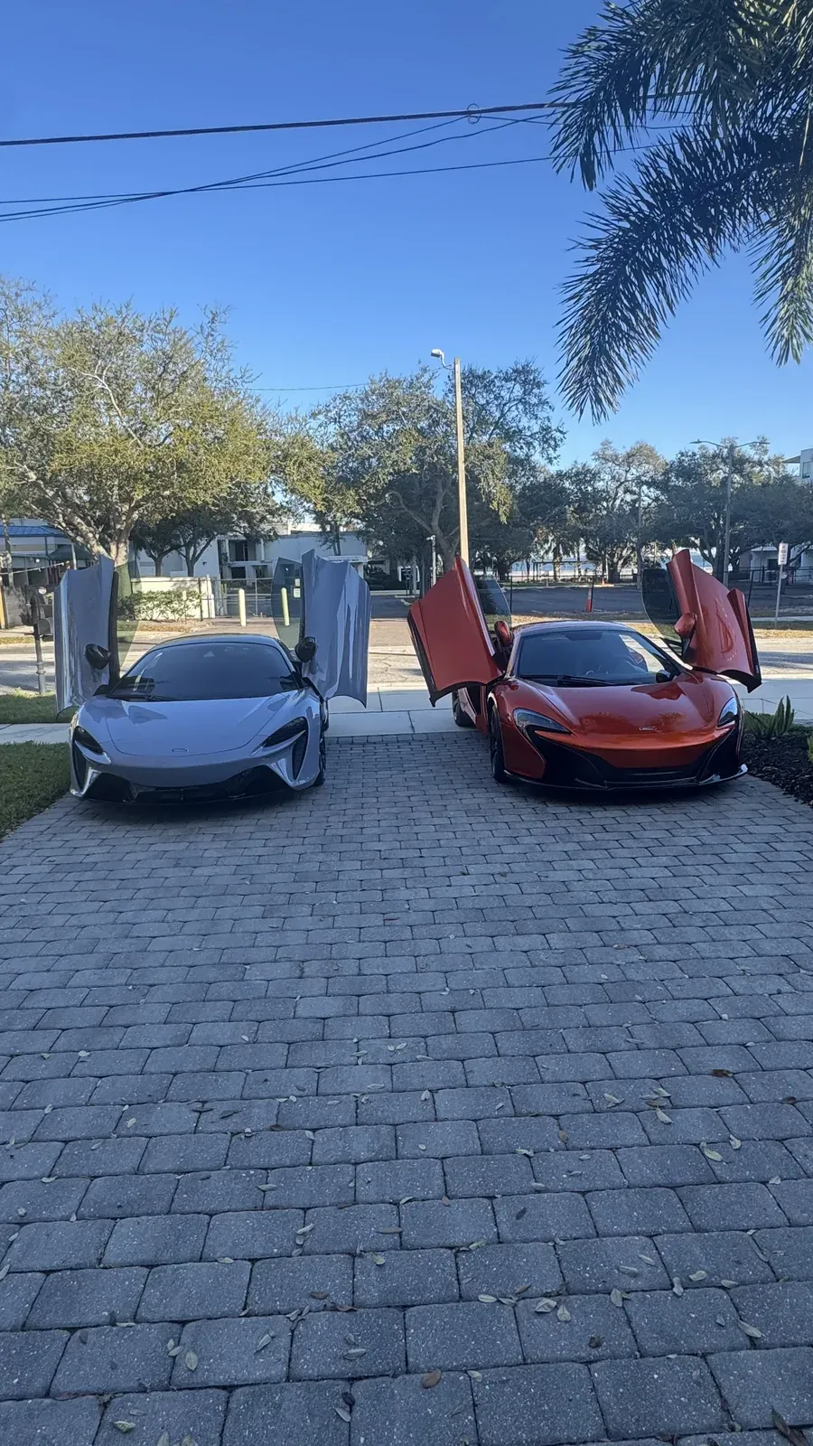 Grey McLaren Artura and orange McLaren parked with doors up after detailing
